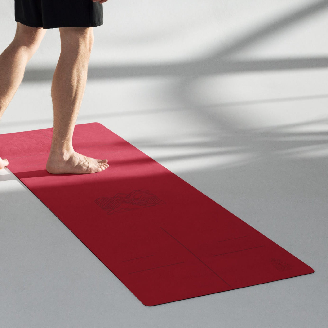 Red suede yoga mat with mountain line art and alignment lines.