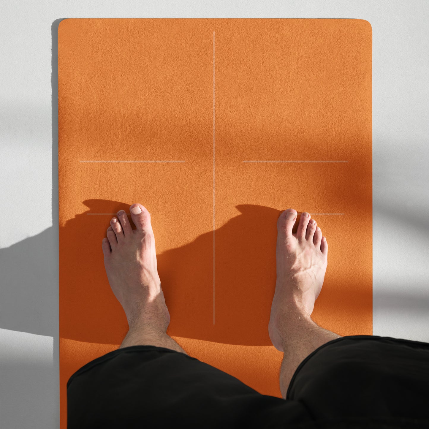 Man standing on the top of the orange suede yoga mat with alignment lines
