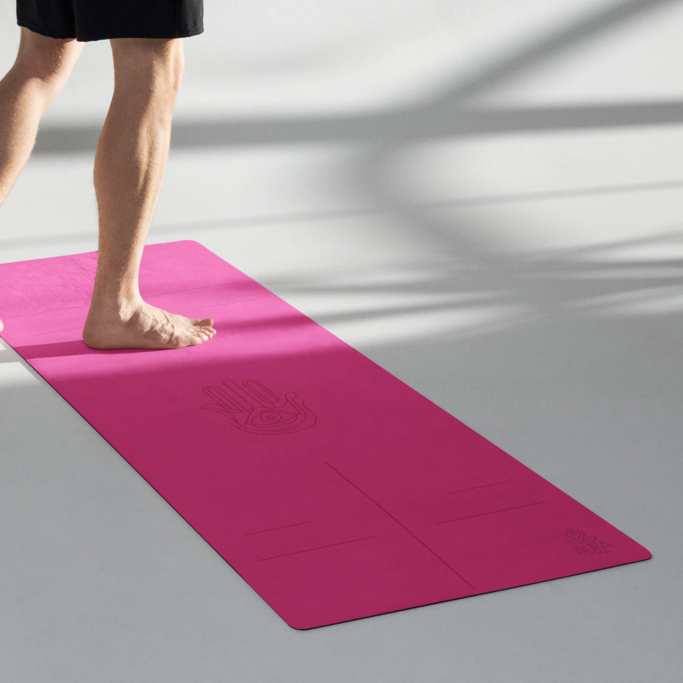 Man standing on a bright pink suede yoga mat with alignment lines