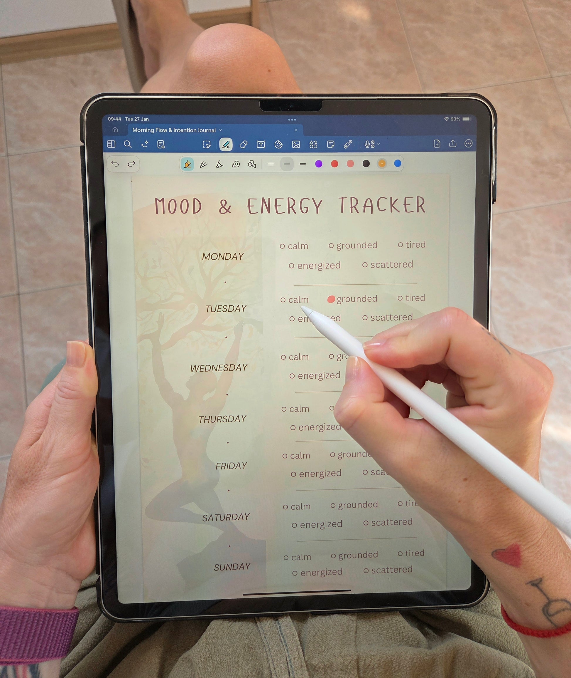 Person using a digital yoga journal on a tablet, writing in a mood and energy tracker page