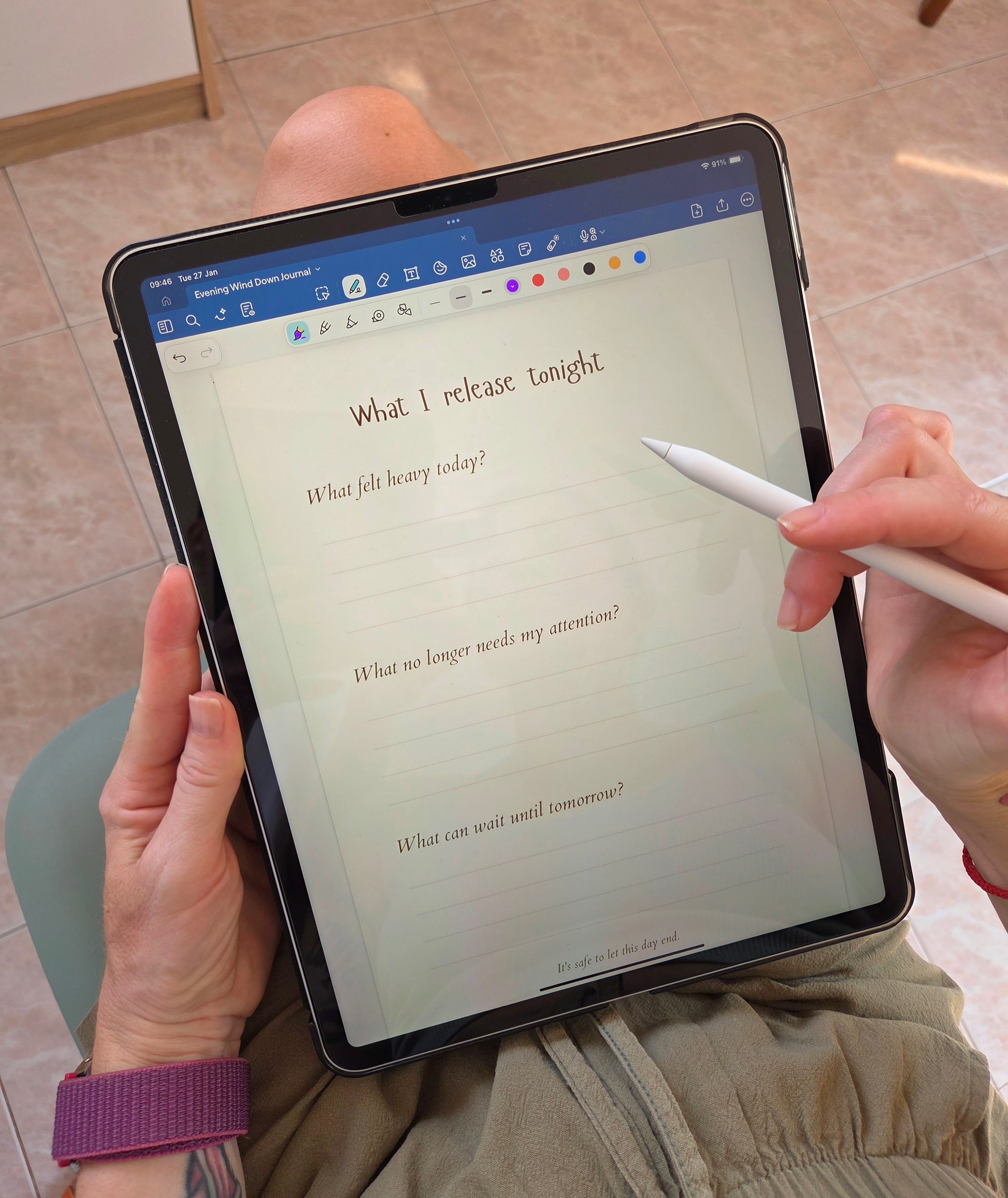Person holding a tablet with an evening self care journal, practicing evening journaling.